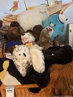 Basket full of assorted plush stuffed animals including a white sheep, blue bird with sailor hat, and various dogs and bears.
