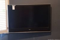 Front view of Sony 45 inch wall-mounted TV on dark wall under window, showing screen and frame