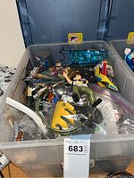 Bin filled with multiple small toys including action figures and building pieces, viewed from above.