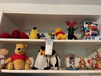 Wide photo of upper and lower shelves showing all toys and plushies in lot including Winnie the Pooh plush, penguin plushies, bird plushes, and Mr. Potato Head boxed and loose toys.
