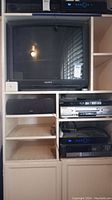 Lot showing Sony CRT TV on top, Panasonic VCR below it and DVD player below the VCR, all in shelving unit.
