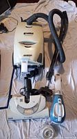 Kenmore Progressive vacuum cleaner with flexible hose, electric floor brush, handheld vacuum, and attachments on white blanket.