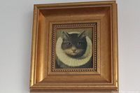 Close up of framed cat portrait showing ornate gold frame and detailed cat face