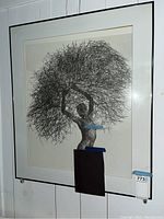 Framed photograph print of a woman holding a large cluster of branches, wall-mounted, shows overall piece and frame condition.
