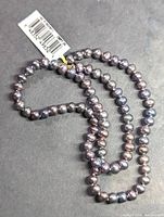 Full view of 17-inch peacock pearl strand necklace showing pearl size and color.