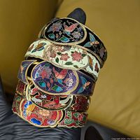 Photo showing stacked five cloisonne style clamper bangle bracelets in varying colorful floral and butterfly enamel designs