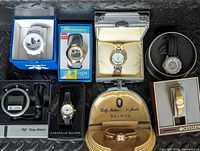 Top view of eight boxed watches showing watch faces, watch boxes and cases including vintage Bulova and other branded watches.