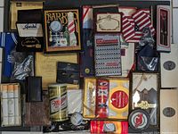 Top-down photo showing full collection of gentlemen's accessories including boxed handkerchiefs, Speidel jewelry items, golf balls, boxed pens, grooming items, and branded packaging.