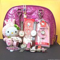 Showcase of all items including pink vinyl Hello Kitty Loungefly tote bag, Hello Kitty plush, various watches, bracelets, and pencil box.