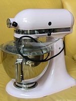 Front three-quarter view of pink mixer with bowl and shield