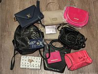 Array of assorted ladies backpacks, handbags, purses and wallets on floor