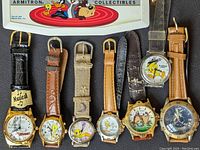 Front view of six Looney Tunes wristwatches alongside Armitron musical watch box featuring character graphics