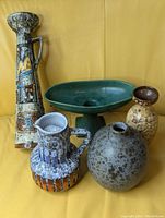 All five ceramic vessels arranged on yellow surface.