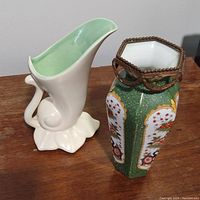Two ceramic vases on wooden surface: cream cornucopia vase and Asian-style vase with green crackle glaze and ormolu trim.