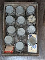 Top view of wooden crate filled with vintage Ball mason jars with metal lids, dusty and aged