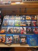 Full collection of 25 superhero Blu-rays laid out showing cover art for identification.