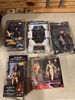 Top-down photo of all five boxed action figures on a table, showing brand logos and packaging condition