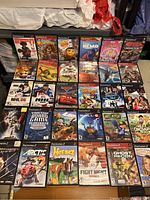 Photo showing multiple PlayStation 2 game cases laid out in rows covering various game-type categories including sports, animated movies, adventure and racing games.