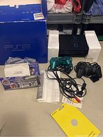 PlayStation 2 console in box with two controllers, AV cable, manuals, and blue retail box with Styrofoam