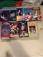 Overall view of the 10 VHS tapes laid on a flat surface showing titles and artwork