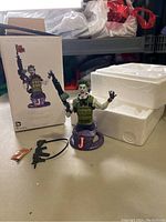 Photo showing the Joker bust with a loose weapon and original box and styrofoam packaging on a table.