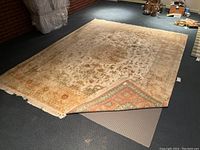 Rug laid flat on floor with one corner folded back revealing underpad