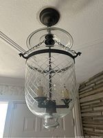 Front view of glass and metal ceiling light mounted on ceiling, showing glass canopy, metal chain, and patterned glass shade