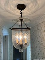 Domed candlestick ceiling light mounted and lit in hallway, showing ceiling fixture and glass dome casting light pattern