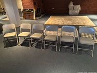 Full view of all six beige folding chairs lined up on floor showing general condition and appearance.