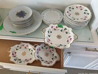 Photo showing various plates and serving dishes including Bavaria and floral antique plates, plus serving platters with pink floral designs and gold accents.