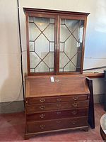 Full view of assembled china cabinet showing upper glass door section and lower cabinet with drawers and drop-front surface
