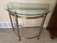 Front view of semi-circle brass table with clear glass top showing fluted legs and curved supports