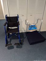 Blue Expedition wheelchair with black fabric seat and padded armrests, footrests visible, on carpeted floor near white louvered doors.