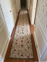 Full length view of floral runner in hallway with beige background and red, pink, green floral design.