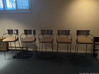 Five metal frame barstools with beige patterned cushions arranged in a row
