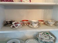 View of all six tea cups and saucers displayed on a shelf showing different designs and colors
