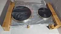 Photo of packaged double burner cooktop wrapped in plastic with cardboard protection.