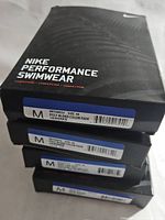 Stack of Nike Performance Swimwear boxes with size 38 poly blend color fade style.