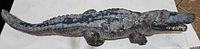 Front view of 27-inch long cement alligator statue showing detailed textured body, legs, and head with open mouth.