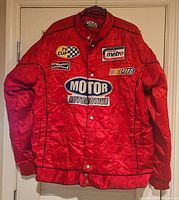 Front view of red quilted 212 NYC racing jacket showing patches and snap button closure