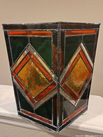 Octagonal stained glass panel showing geometric patterns with yellow, orange, green, and red hues.