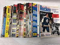 Front view of 24 vintage NHL hockey magazines from the 1970s, arranged side by side showing colorful covers with players and team headlines
