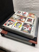 Two black and brown binders filled with hockey cards in clear plastic sleeves.