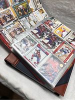 Open binder showing hockey cards featuring players like Kirk Muller and others from various teams
