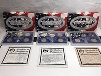 Three plastic display cases with five quarters each, inside patriotic cardboard holders, along with three certificates of authenticity.