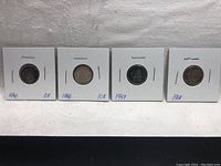 Four Canadian dimes in white cardboard holders marked with dates and denomination.