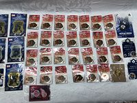 Display of multiple Hockey Canada 2006 collector pins still in sealed blister packs and loose, laid out on a fabric surface with player images and logos.