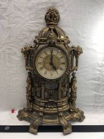 Front view of gilded mantel clock showing full case and dial
