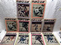 Ten 1970s Toronto Maple Leafs game programs laid out, showing colorful covers with players in various hockey action poses.