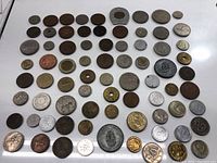 Wide view of 55 coins arranged in rows showing a variety of sizes, colors, and designs from different countries.